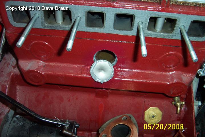 Poorly installed core plug.jpg - Removing the manifolds revealed the JB Weld had not been allowed to set up. Also, notice the excessive dimple in the center of the plug. The plug was never seated correctly. We fixed both problems.